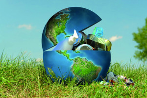 Earth globe in grass filled with assorted trash - concept representing environmental contamination of our planet by people and industry